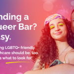 An image featuring two LGBTQ+ people with white text that reads, “Finding a Queer Bar? Easy. Finding LGBTQ+ friendly healthcare should be, too. Here’s what to look for.” The background is a gradient that flows in vibrant shades of purple, pink, and peach. Graphic elements on the background include glitter and bubbles.